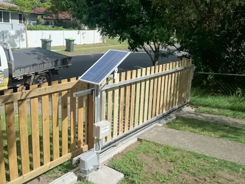 Technician installing solar sliding gate automation system for residential property.