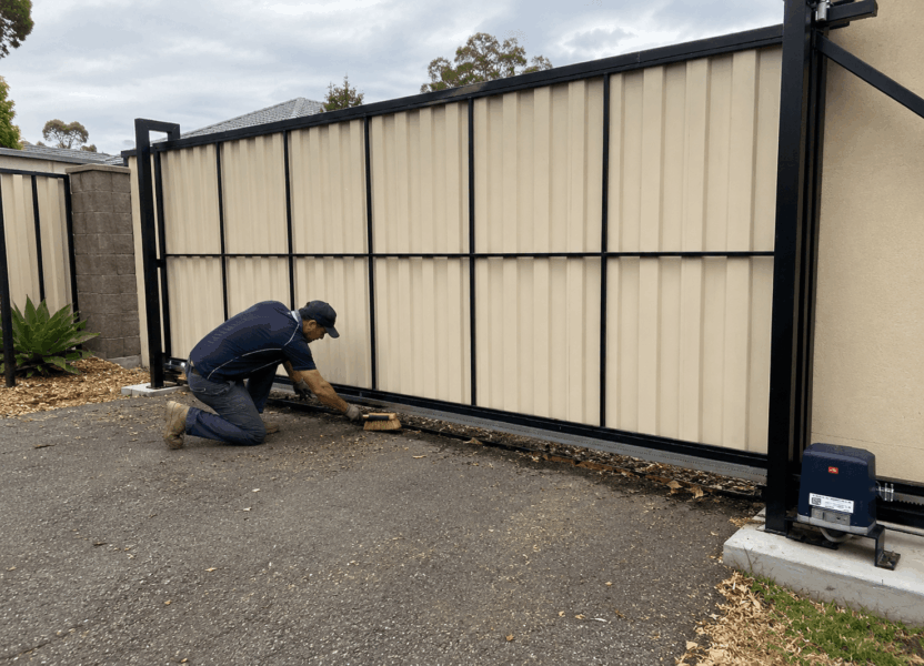 A person cleaning the rail may be bending down, working close to the gate leaf or concentrating on debris near the wheels.